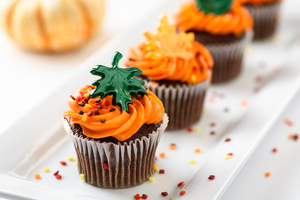 Autumn delicious cupcakes decorated with orange frosting, sprinkles and maple leaves