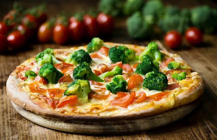 Fresh baked pizza with broccoli florets, sliced tomatoes drizzled with Hollandaise sauce.