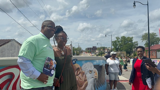 muralist and mayor in front of military themed  painting 