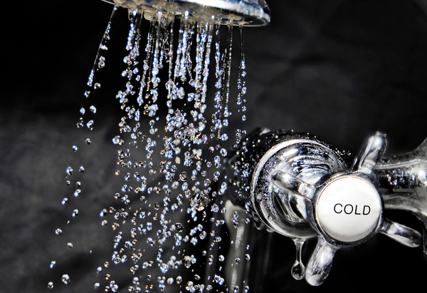 Cool down with water - Chrome bath tap and water flowing from shower head