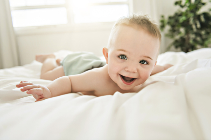 A cute baby boy lying on a white bed