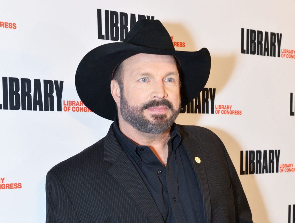 Garth Broks Poad Tribute To Elton John- Garth on the red carpet wearing a black suit and hat. 